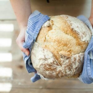 Person Holding Baked Pastry Covered With Towel